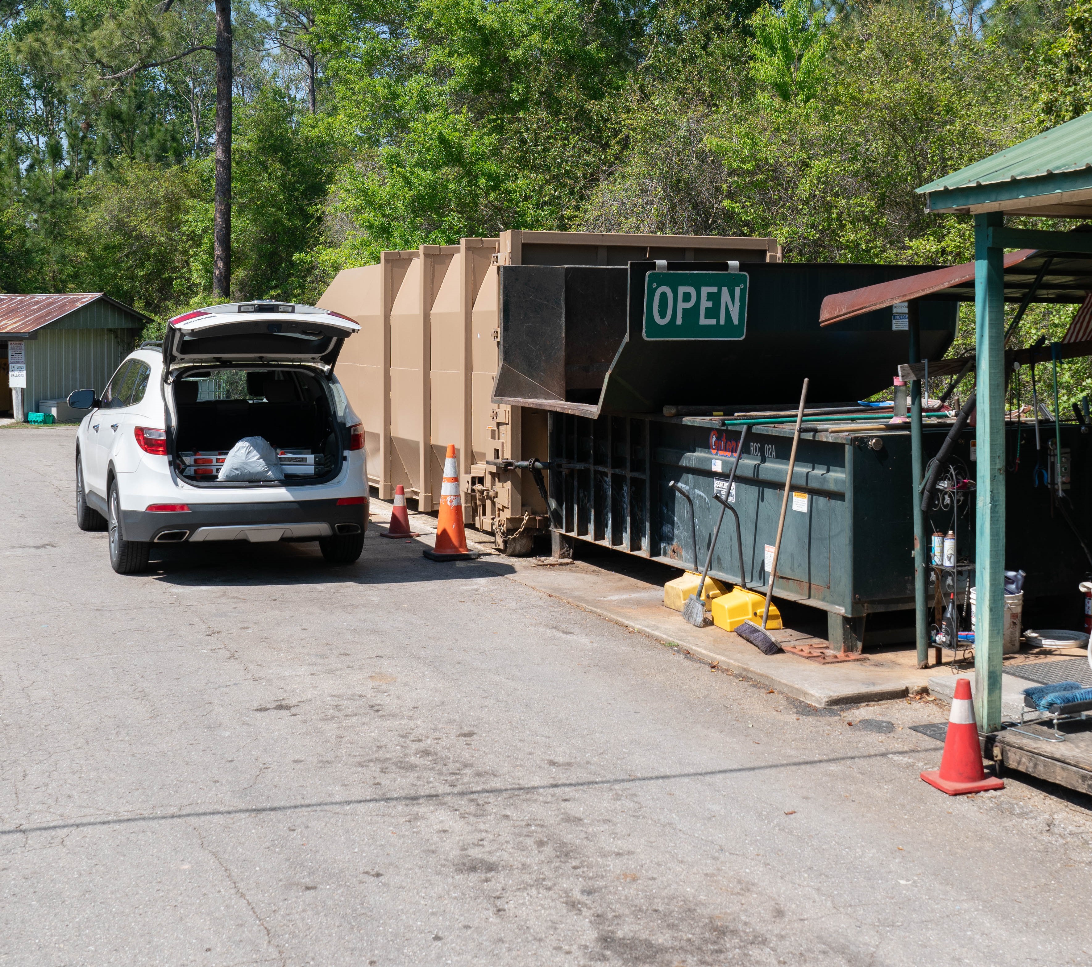 Image of Collection center attendant Helping customer alongside trash compactor.